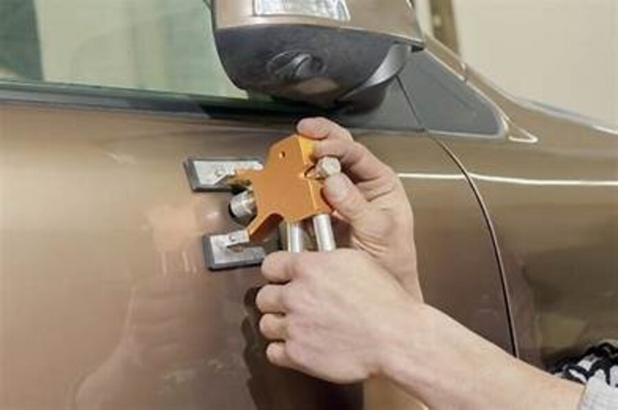 Dent lifter tool removing a ding from an SUV door