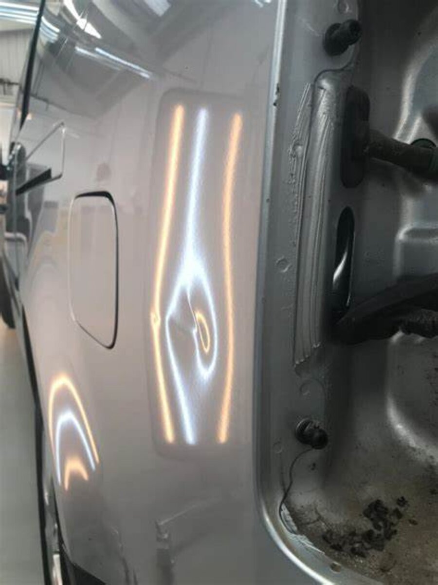 Dent repair on a silver van panel under PDR light